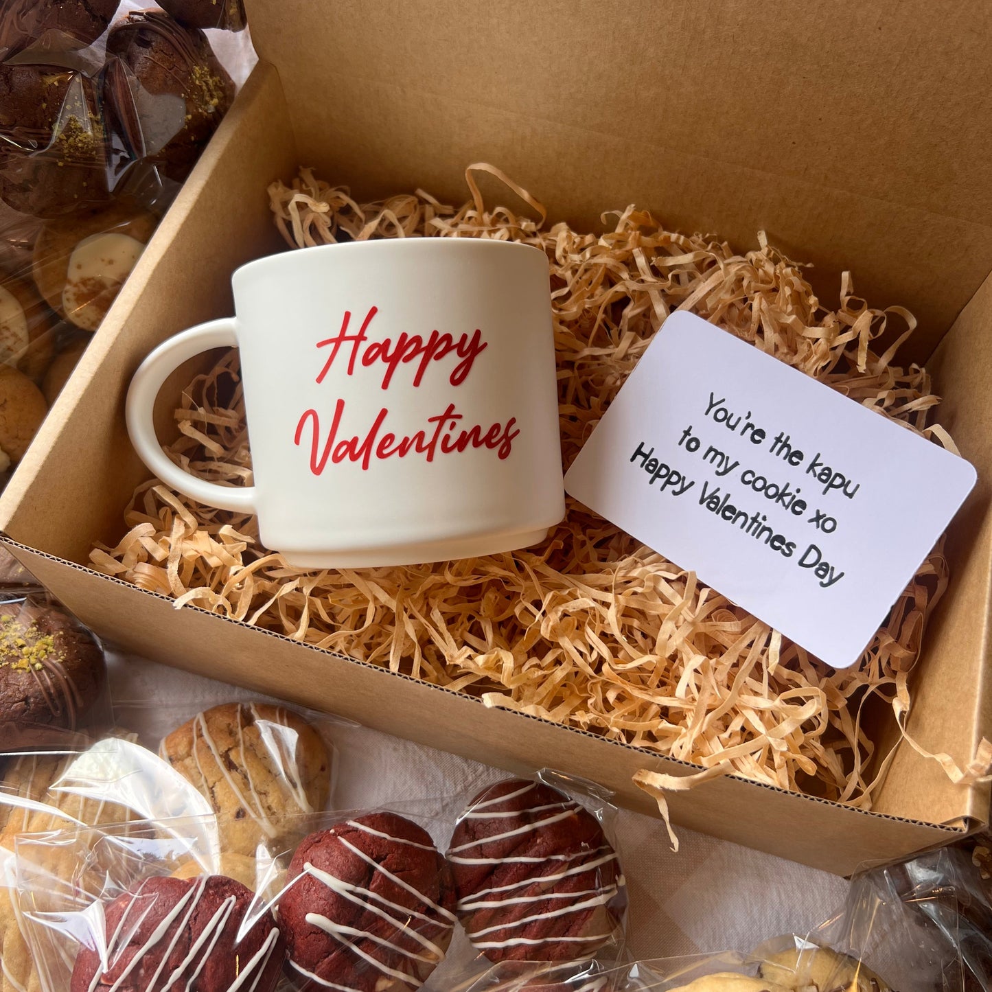Valentine's Day gift box with a personalised kapu (cup), cookies and a card inside.